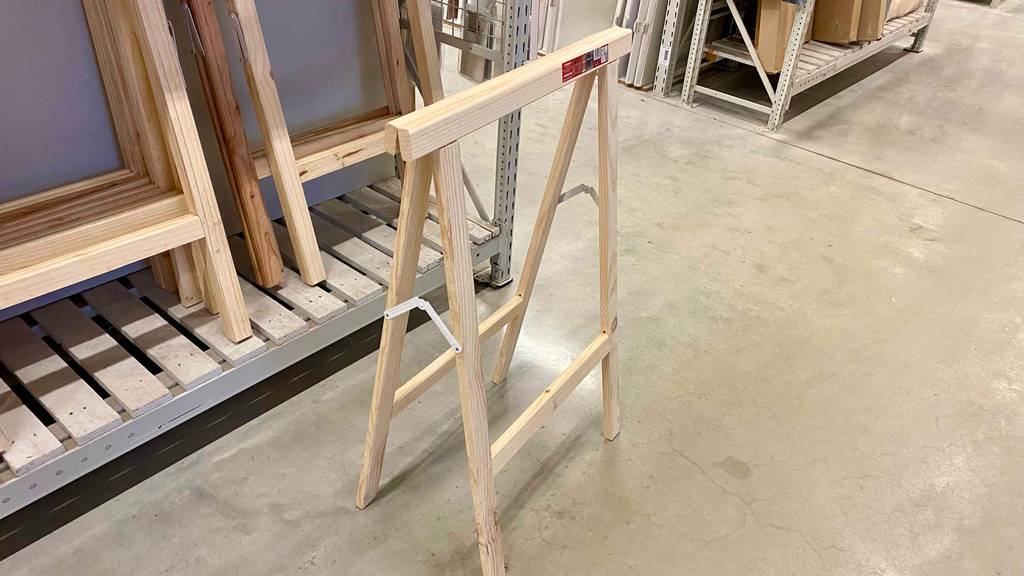Klappbock-Test: ein Modell aus Holz steht halb aufgeklappt in einem Verkaufsbereich vor einem Regal mit weiteren Holz-Klappböcken.