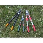 Die getesteten Astscheren liegen nebeneinander im Gras.