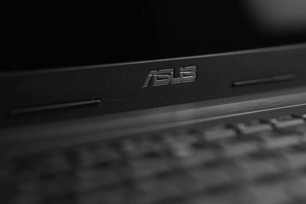 Getestet: Nahaufnahme des Herstellerlogos unterhalb des Bildschirmes eines Asus-Laptops.