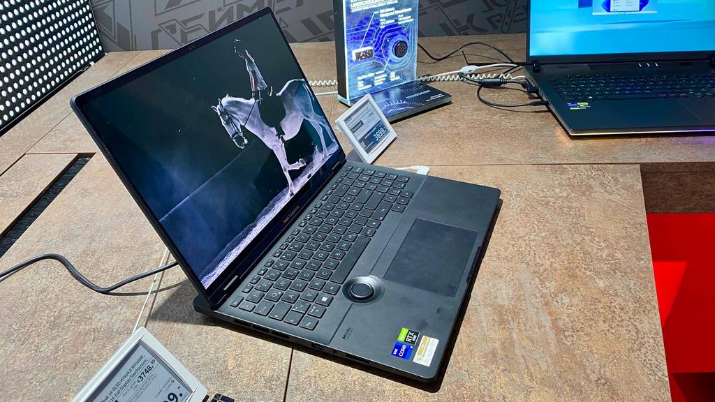 Asus Notebook mit Touchscreen im Test befindet sich eingeschaltet auf einem Ausstellungstisch in einem Verkaufsbereich.