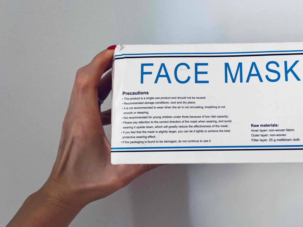 Atemschutzmaske im Test: Eine Hand hält die Originalverpackung vor eine helle Wand.