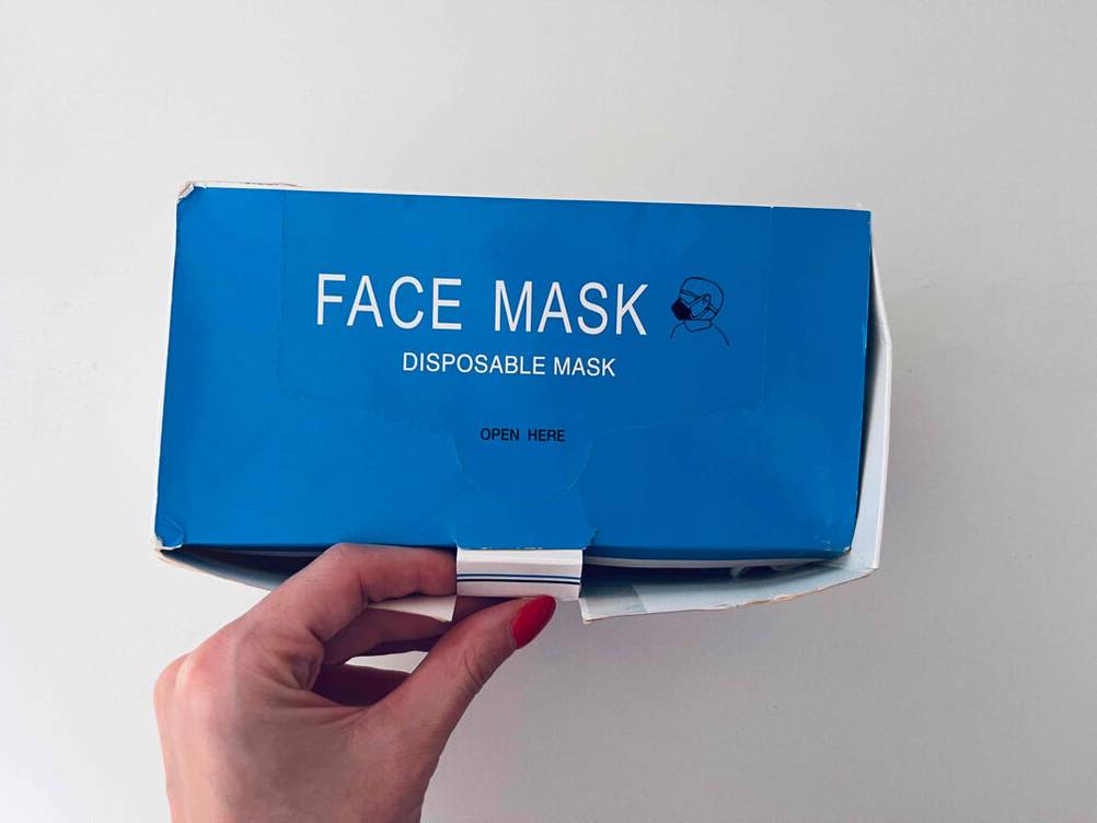 Eine Hand öffnet eine Packung der Atemschutzmasken im Test.