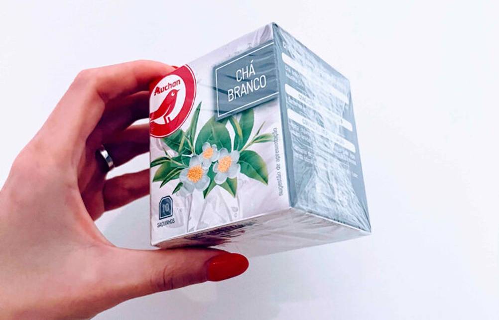 Weißer Tee im Test: Eine Damenhand hält eine Packung inklusive zehn Teebeutel vor einem weißen Hintergrund.