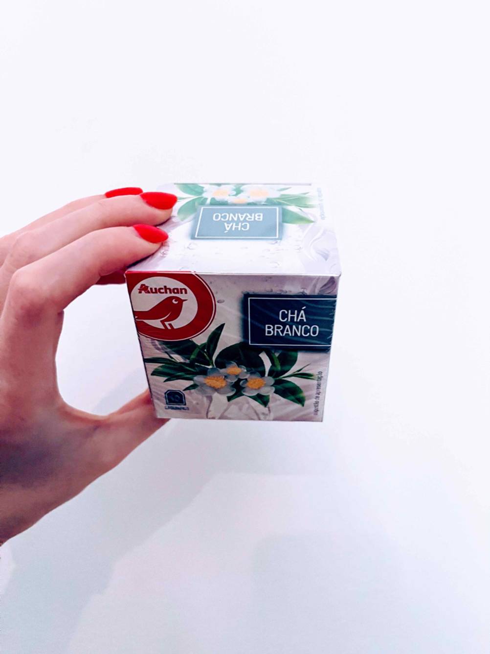 Getestet: Eine Hand hält eine Packung Weißer Tee vor eine helle Fläche.