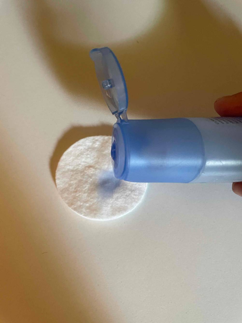 Eine Hand schüttet etwas des getesteten Augen-Make-up-Entferners auf ein Wattepad.