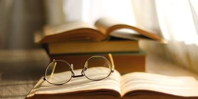 Brille liegt auf aufgeschlagenem Buch.