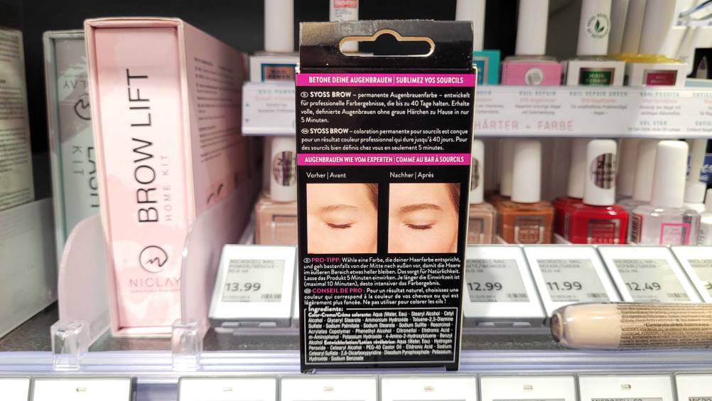 Eine Packung der getesteten Augenbrauenfarbe von hinten vor einem Regal.