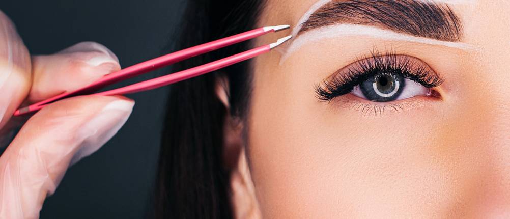 Augenbrauenpinzette im Test - pink-beschichtete Pinzette zupft Augenbraue, die Augenbraue ist weiß umrandet. 