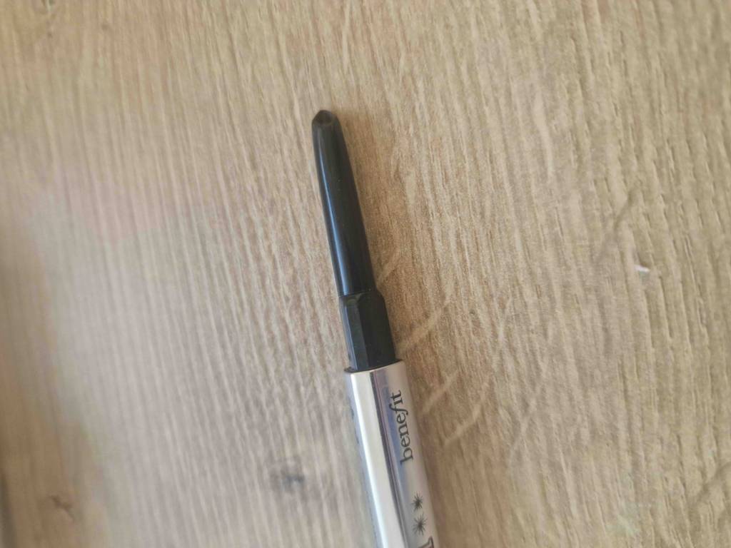 Augenbrauenstift getestet: Nahaufnahme eines Stiftes ohne Kappe auf einer Holzfläche.