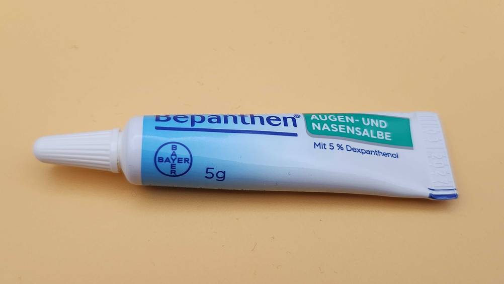 Augensalbe im Test: Eine Tube horizontal auf einer gelben Fläche.