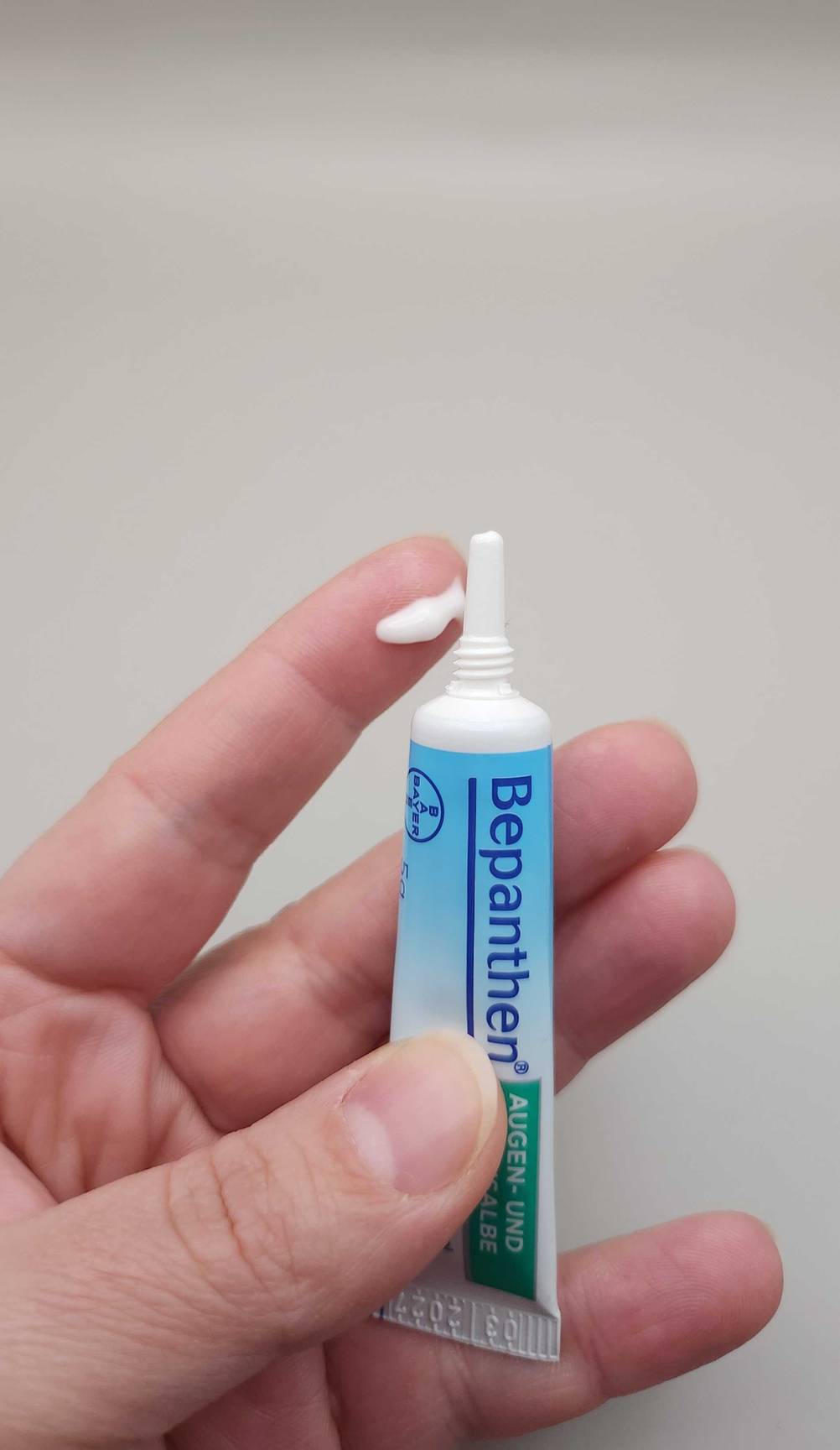 Eine Han hält eine Tube der getesteten Augensalbe und hat Salbe am Finger.