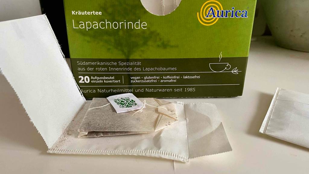 Lapacho-Tees im Test: ein ausgepackter Teebeutel liegt auf seiner weißen Verpackung vor einer grünen Schachtel mit Kräutertee der Marke Aurica.