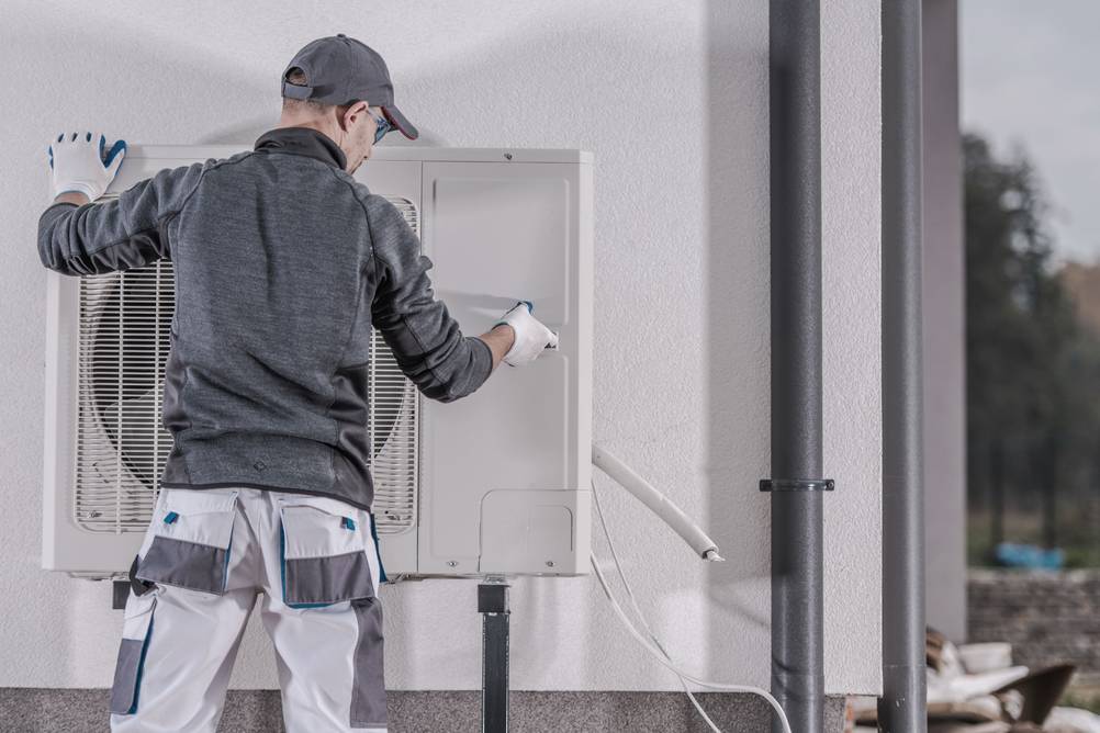 Handwerker demontiert eine alte Wärmepumpe.