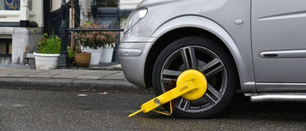 Auto am Straßenrand. Das linke Vorderrad ist durch eine Parkkralle geschützt
