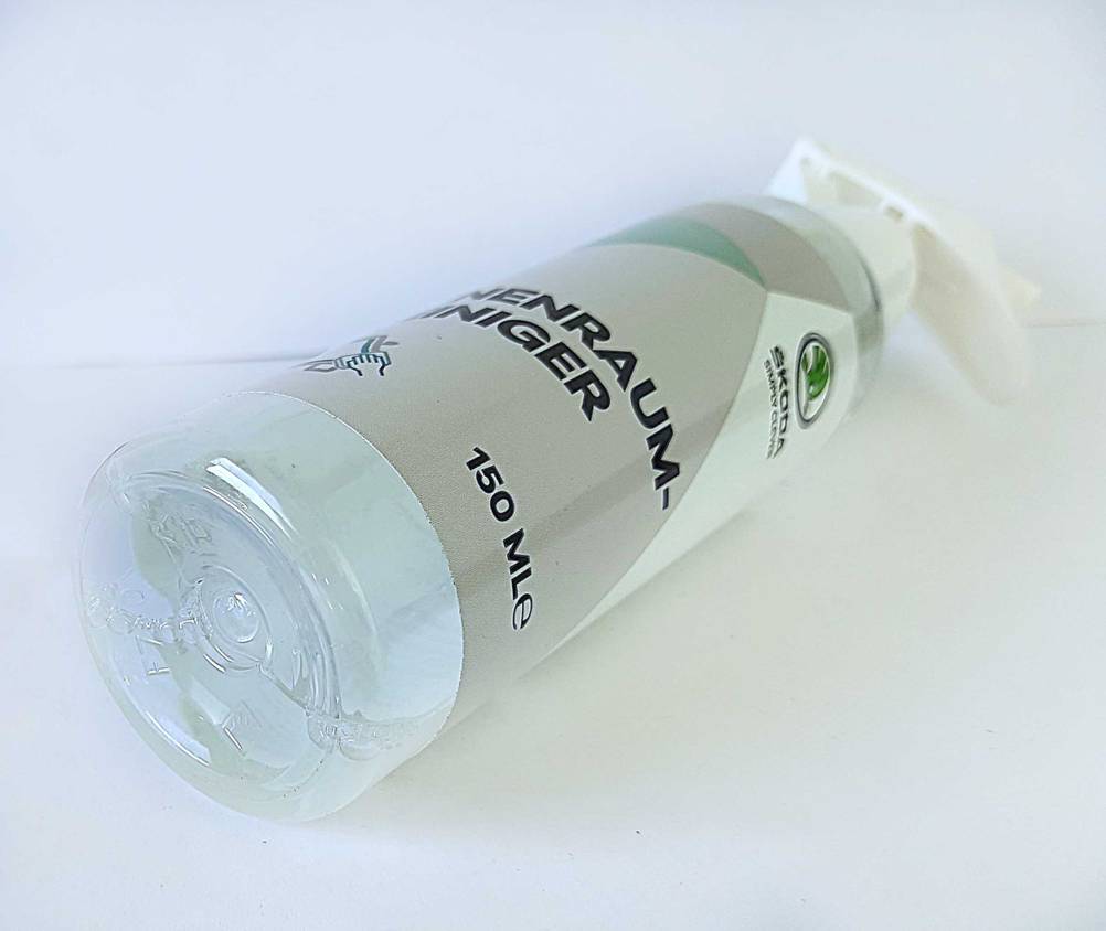 Die Flasche des getesteten Auto-Innenraumreinigers mit dem Boden nach vorne auf einer hellen Fläche.