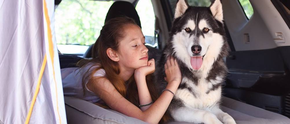 Auto-Luftmatratze getestet: Mädchen mit Hund auf einer Luftmatratze im Kofferraum