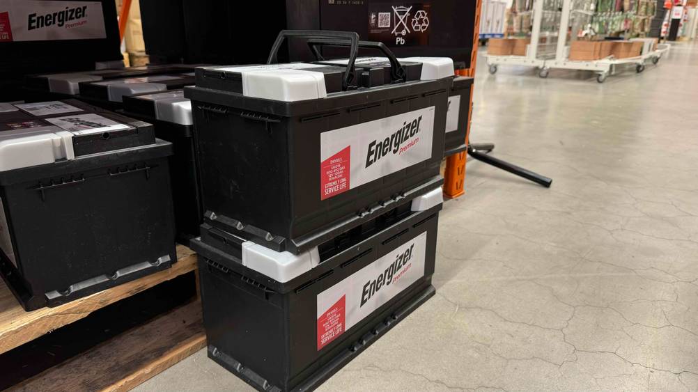 Autobatterie 100Ah getestet: Zwei Batterien übereinander von schräg seitlich vor einem Regal.