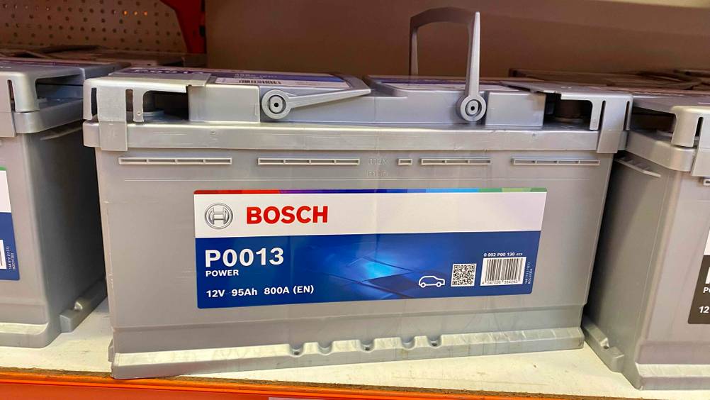 Autobatterie 95Ah getestet: Eine Batterie von vorne in einem Regal neben anderen stehend.