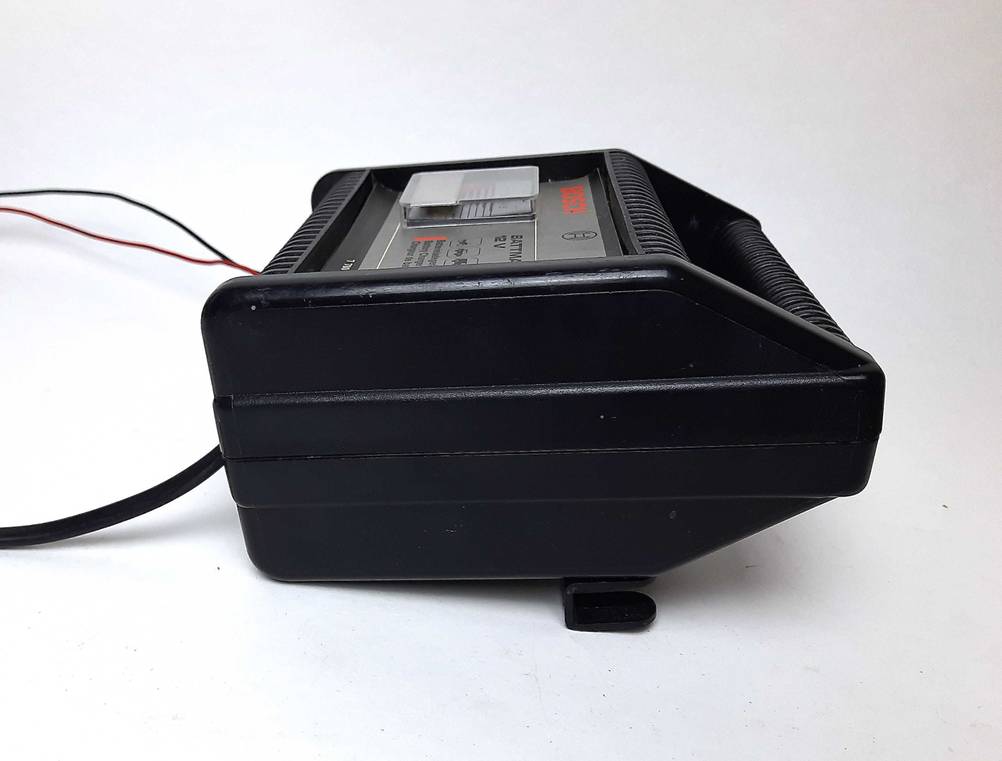 Seitenansicht des getesteten Autobatterie-Ladegerätes auf einer hellen Fläche liegend.