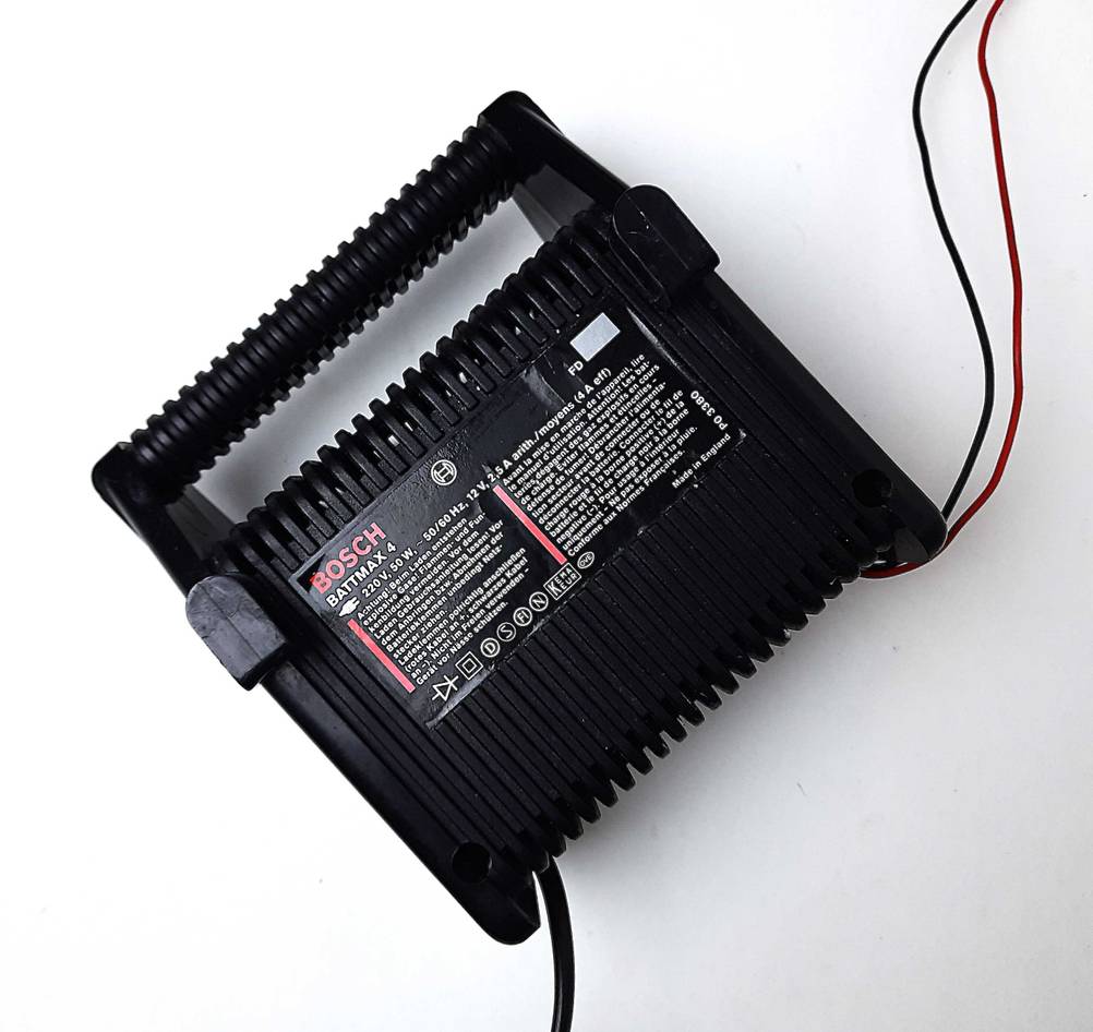Das getestete Autobatterie-Ladegerät von hinten mit Kabeln.