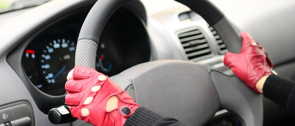Autofahrer-Handschuhe im Test: Hände in roten Handschuhen sind an ein Autolenkrad angelegt.