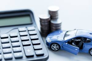 Autokredit-Vergleich: Neben einigen Münzen und einem Modelauto liegt ein Taschenrechner.