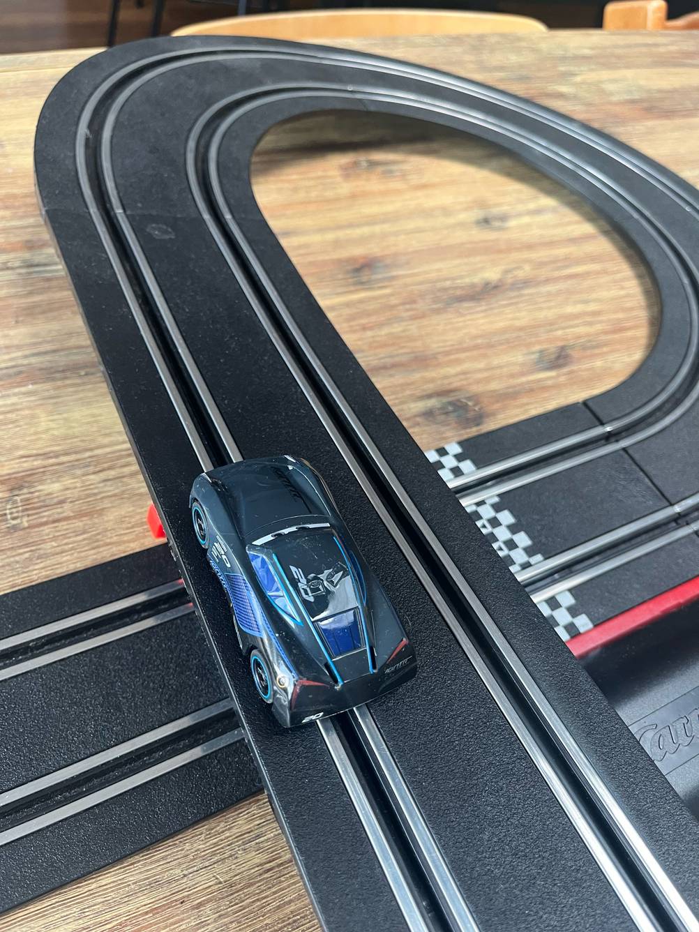 Auf einer getesteten Autorennbahn befindet sich ein Auto in einer Spur, es ist eine Kurve zu sehen.