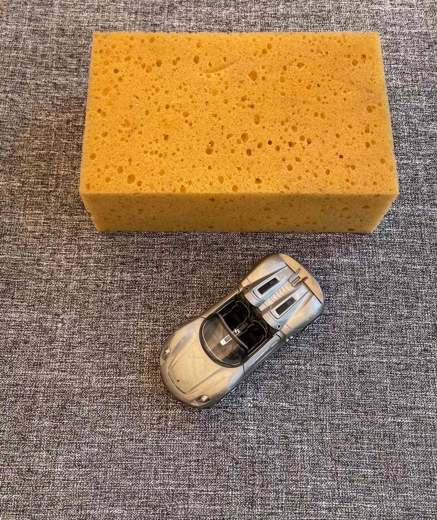 Autoschwamm getestet: Autoschwamm liegt auf grauem Untergrund mit einem Spielzeugauto.