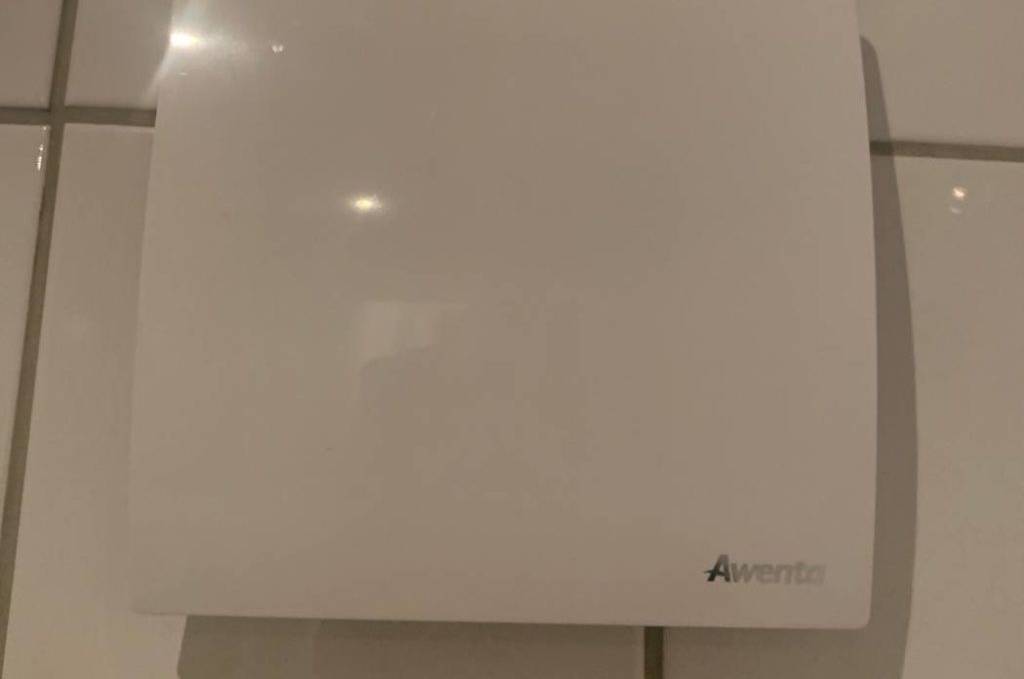 Badlüfter im Test: ein quadratisches Modell der Marke Awenta auf einer hellen Fliesenwand.