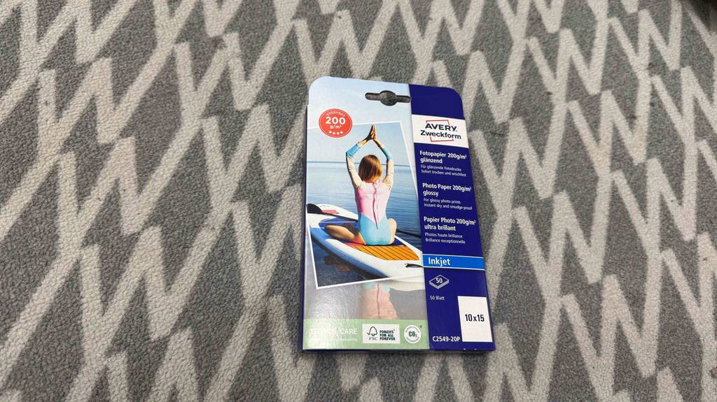 Eine Packung Fotopapier 10x15 liegt zum testen auf einem Teppichboden.