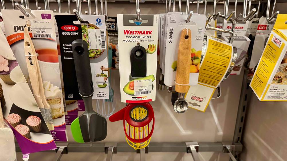 Mehrere getestete Avocadoschneider hängen in einem Verkaufsregal neben anderen Produkten.