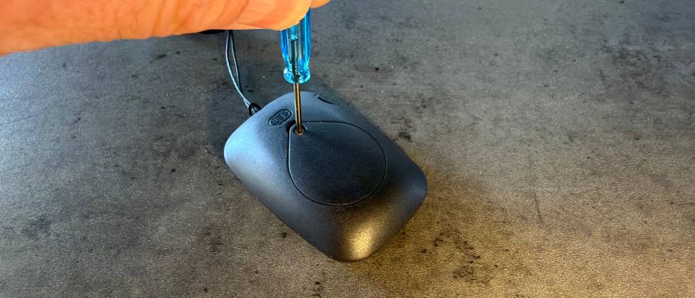 Eine Hand schraubt das Batteriefach vom Avtrek-3D-Schrittzähler auf