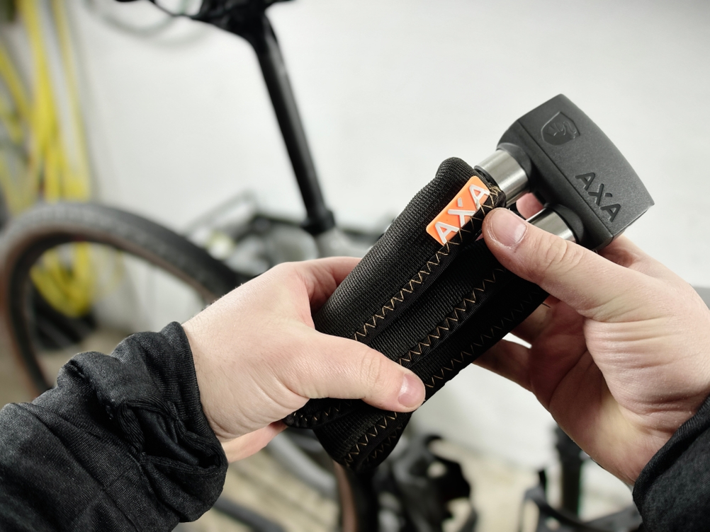 Das Axa Foldable 600 wird zusammengefaltet in zwei Händen gehalten. Die Glieder sind kompakt übereinandergelegt.