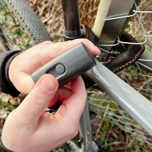 Der Zylinder des Axa Foldable 600 wird mit geschlossenem Regenschutz gezeigt. Eine Hand hält das Schloss.