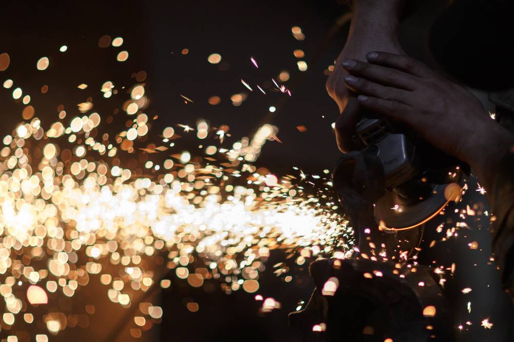 Axtschärfer im Test: eine kaum erkennbare Axt wird mit einer Flex bearbeitet, der starke Funkenflug steht im Vordergrund.