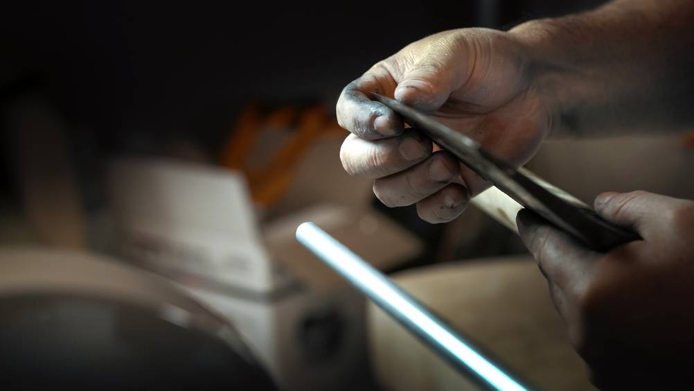 Axtschärfer im Test: Eine Axtschneide wird in den Händen gehalten und die Klinge befühlt.