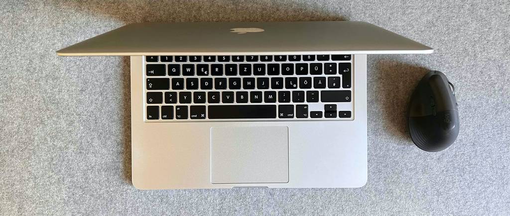 Apple MacBook im Test: Offener Computer und Maus auf einer grauen Oberfläche