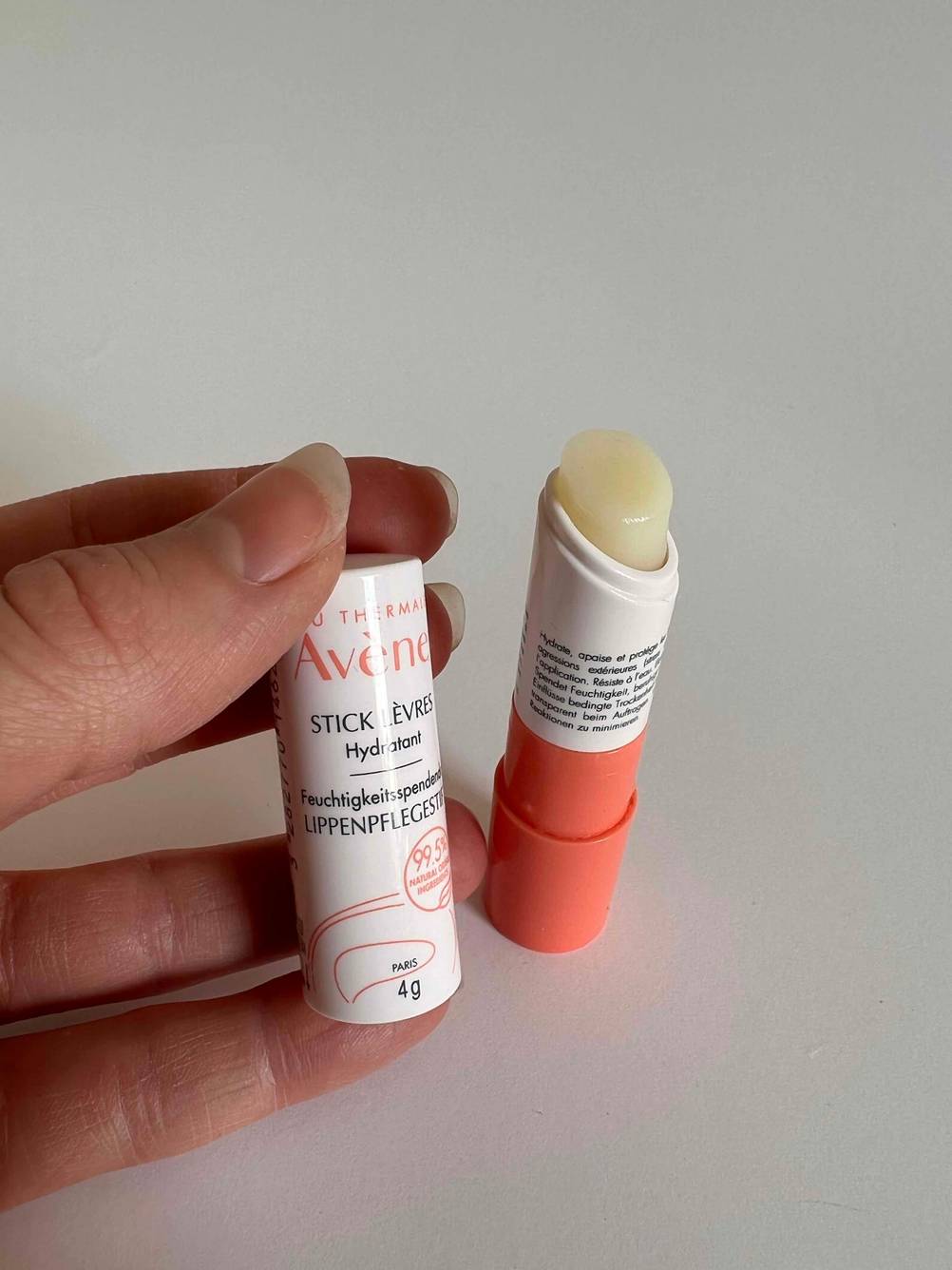 Lippenpflegestift geöffnet und Verschluss in der Hand.