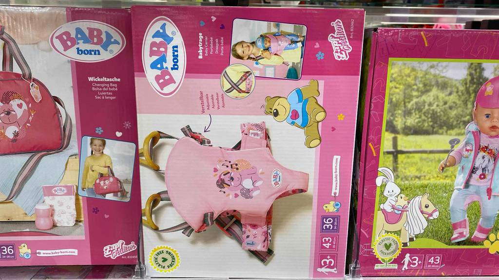 Baby Born Puppentrage im Test: Eine Verpackung mit einem rosa Puppentrage-Bild steht in einem Verkaufsregal zwischen anderen Babyartikeln.