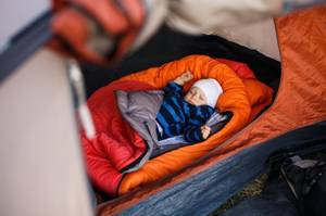 Kinderschlafsack-Test: Ein Baby liegt in einem Schlafsack in einem Kinderwagen. 