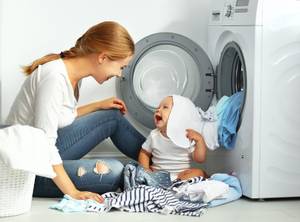 Baby und Mutter neben Waschmaschine