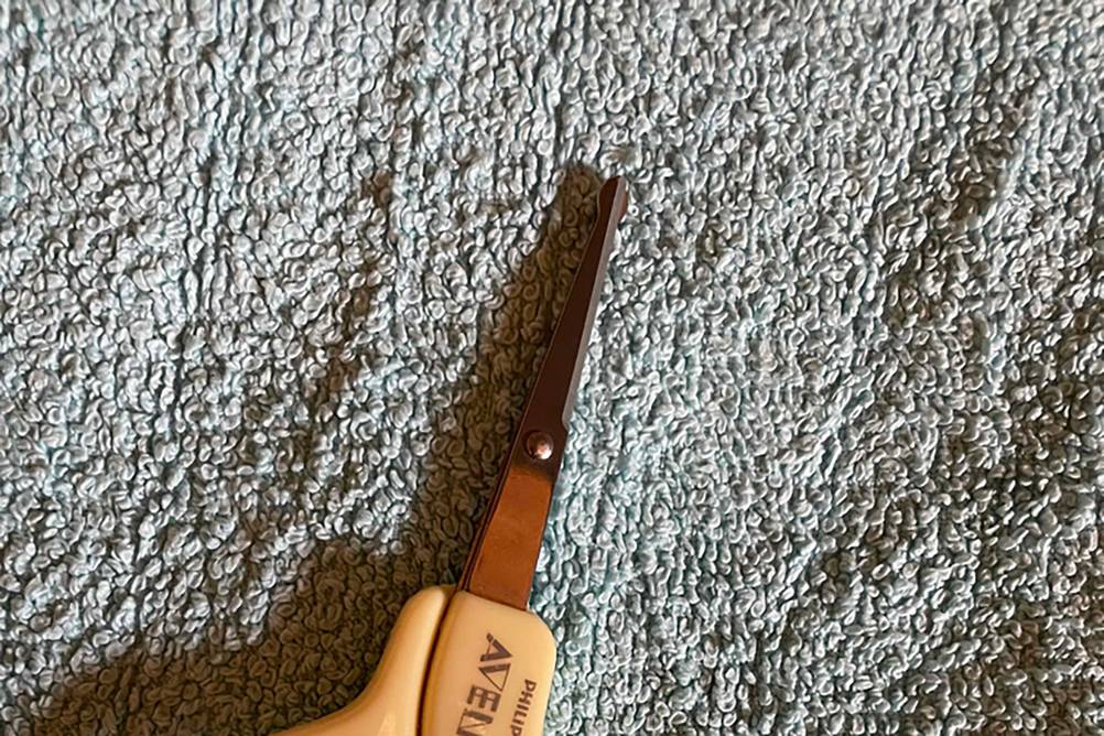 Nahaufnahme der Klingen einer getesteten Baby-Nagelschere auf einem grauen Handtuch.