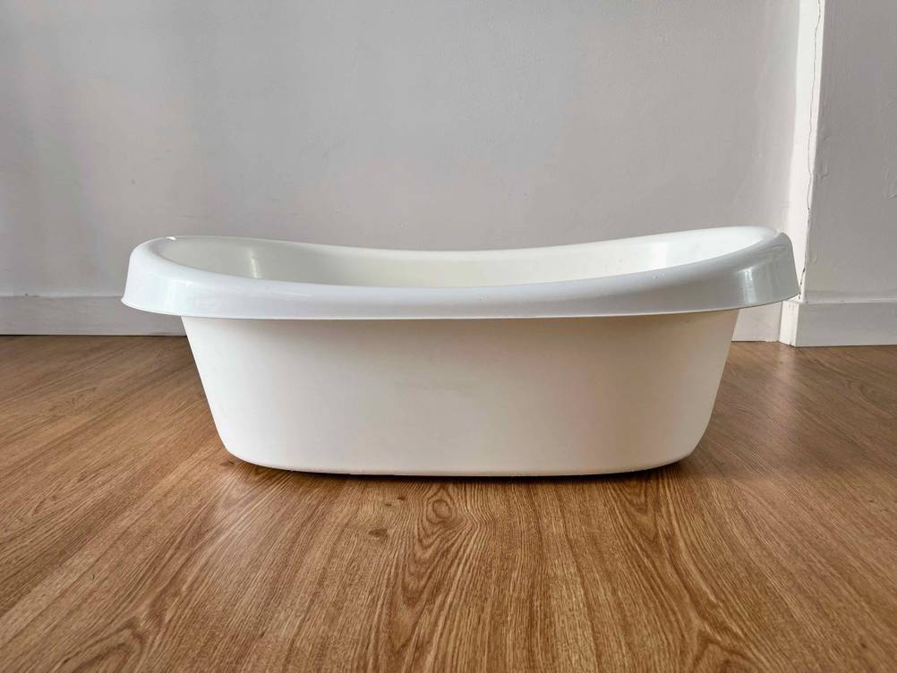Seitenansicht einer getesteten Babybadewanne auf einem Holzboden.