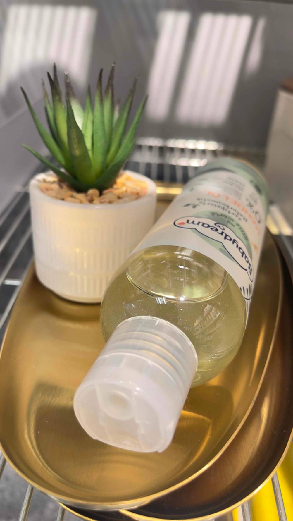 Eine Flasche Mandelöl für das Baby liegt zum testen mit dem Deckel nach vor auf einer Schale.