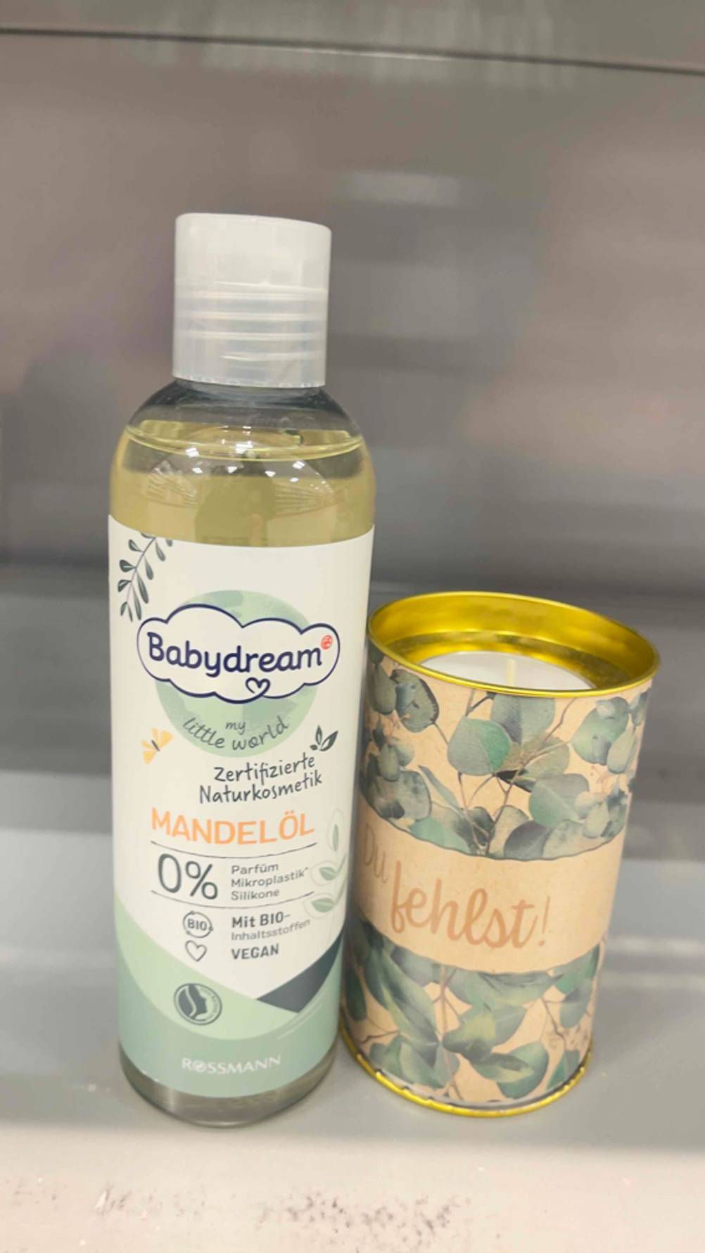 Mandelöl für das Baby im Test: Eine Flasche steht neben einer Kerze.