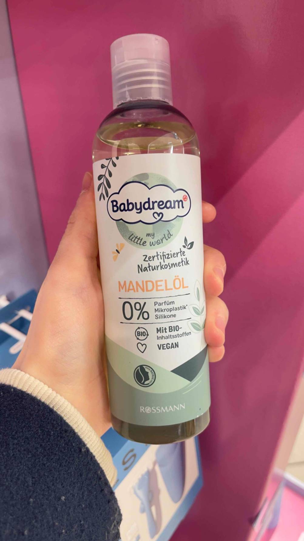 Im Test: Eine Hand hält eine Flasche Mandelöl für das Baby.