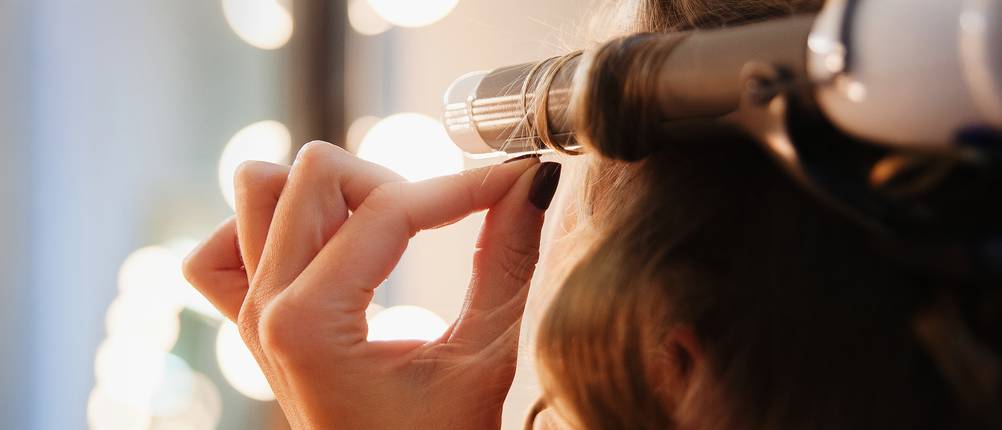 BaByliss Lockenstab Test: Eine Frau lockt sich die Haare.