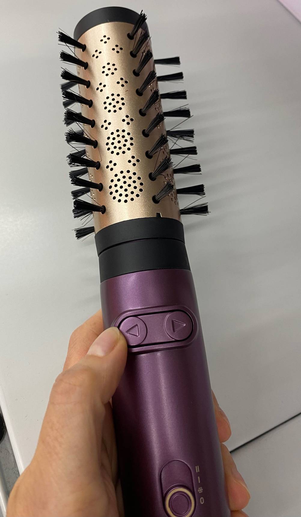 Eine Hand hält eine getestete Babyliss-Warmluftbürste mit verstellbaren Heißluftstufen. 