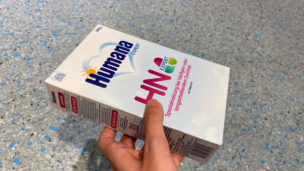 In der Hand befindet sich eine Packung getestete Babynahrung. 