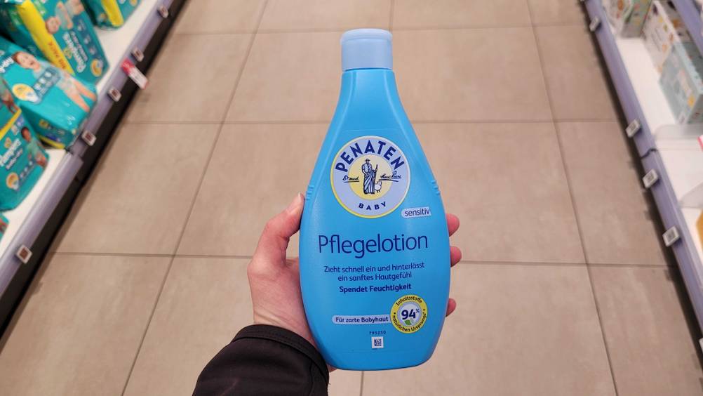 Eine Hand hält das getestete Babypflegeprodukt hoch.